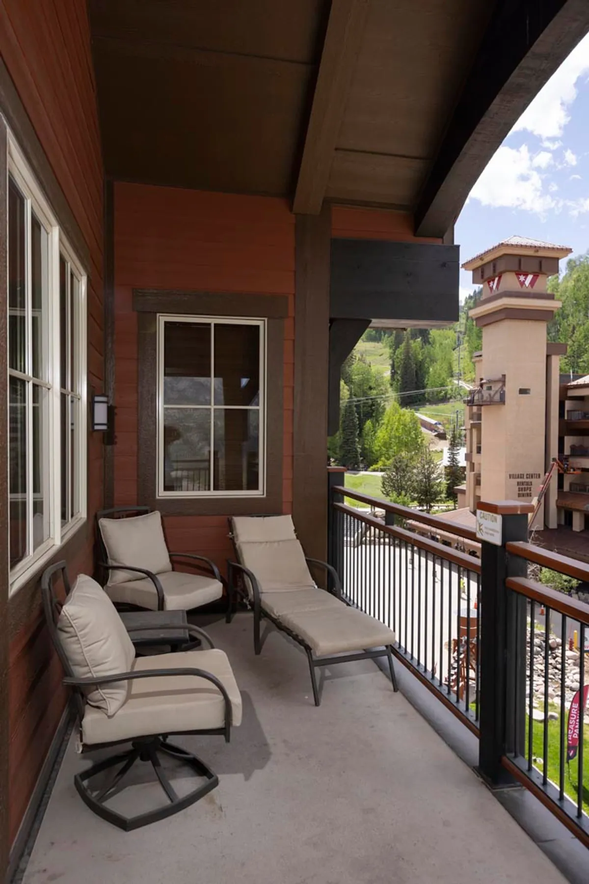 This image offers a close-up of an outdoor balcony seating area overlooking a scenic mountain vista. The inviting space is ideal for relaxing after a day outdoors, savoring the fresh mountain air and the cooling evening breezes described in the section.