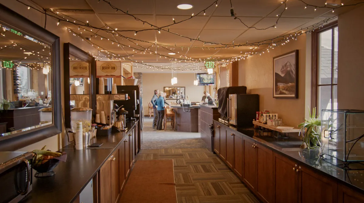 A stylish bar area and coffee station with decorative lighting and wall art, creating a cozy atmosphere for socializing, enjoying drinks, or morning coffee rituals. The layout encourages group interaction and relaxation.