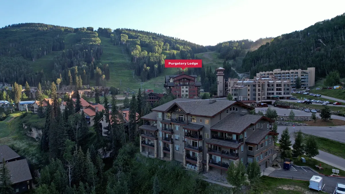 This exterior shot of Purgatory Lodge captures the building set against a backdrop of mountains and a tree line, hinting at the natural beauty and adventure available right outside the lodge. The parking area and entrance offer a sense of arrival and gathering, suitable for families or larger groups.